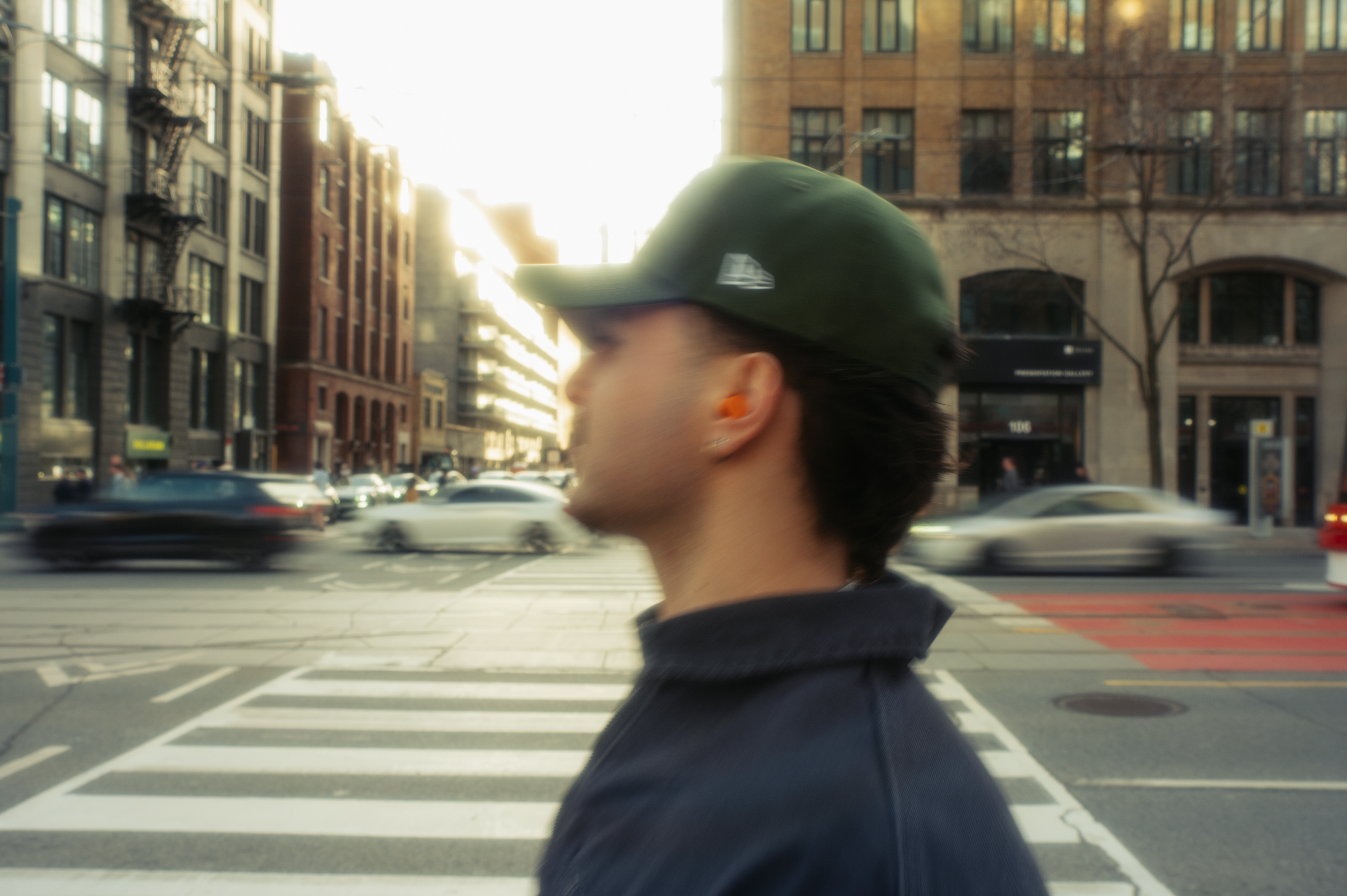 JOZY walking through a busy city intersection in profile