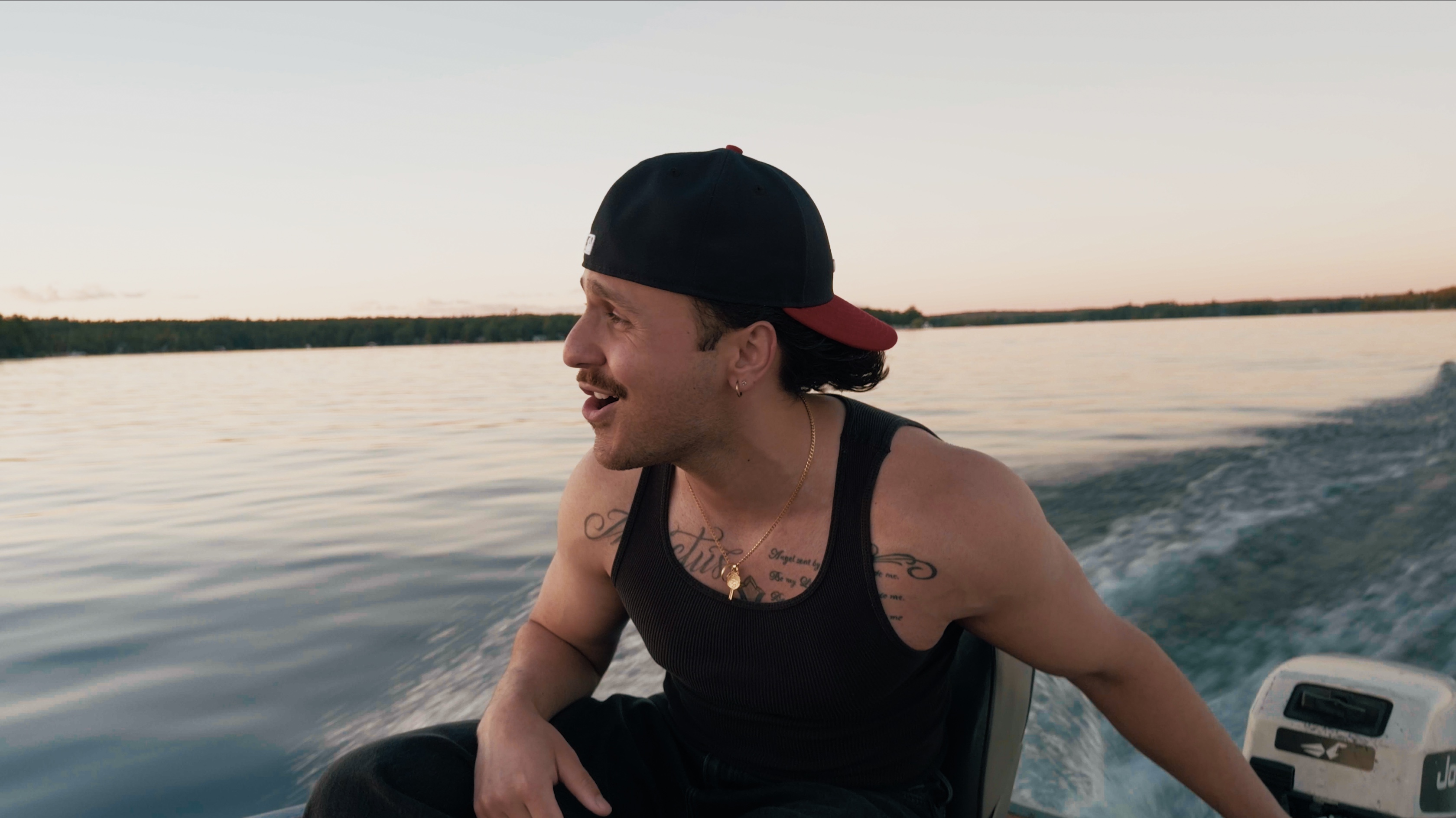 JOZY laughing while riding a motorboat at dusk