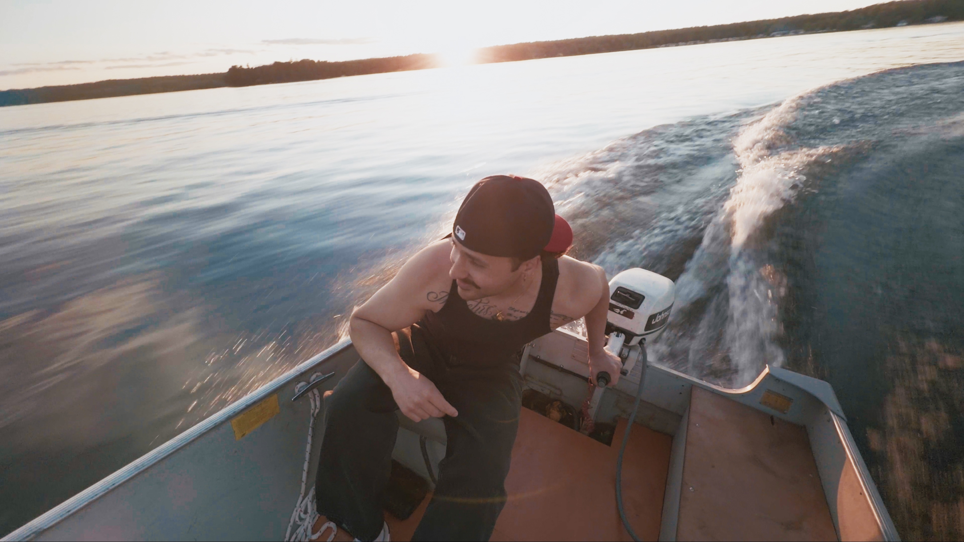 JOZY steering a boat across calm water at sunset